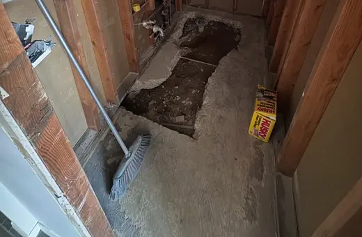 Half-bathroom being converted to a full bathroom, gutted and slab opened to prep for new plumbing