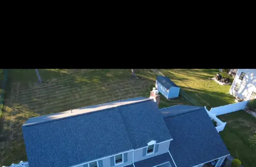 Aerial drone view of a two-story home after a new dark gray asphalt shingle roof installation