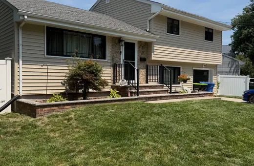 Split-level home exterior with newly built front steps, brick paver retaining wall, and walkway