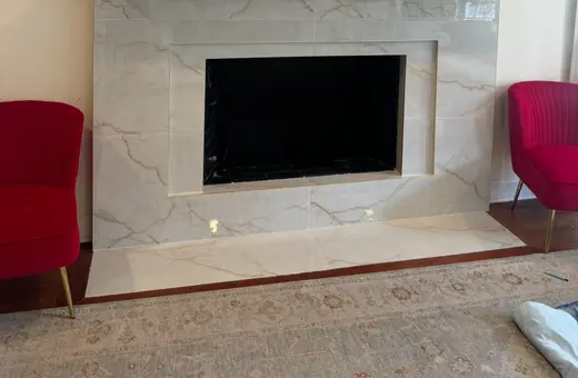 Custom fireplace bump-out with large-format tile and a warm wood mantle for a modern, timeless look