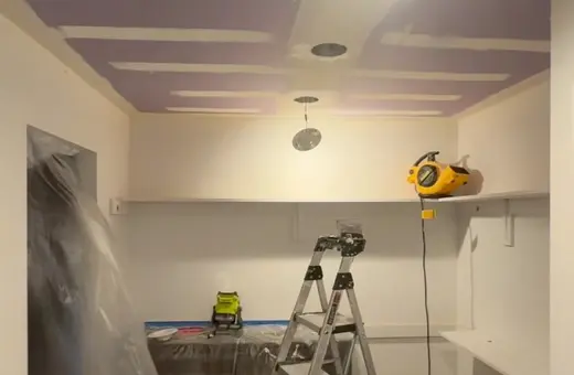 Ceiling drywall patch repairs in progress, with fresh joint compound sections and a ladder set up below